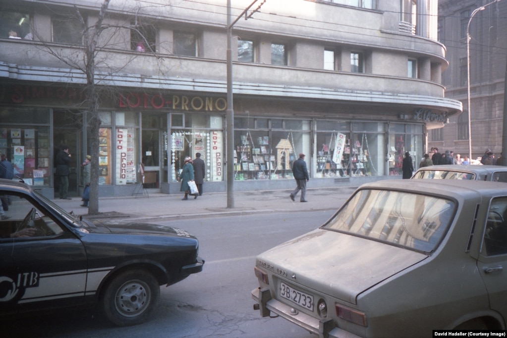 Dyqane në Bukuresht, përfshirë një librari (djathtas) dhe një Loto-Prono, një pikë ku rumunët mund të luanin kumar në një llotari, ose lojëra futbolli rumun ose italian.