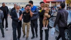 People injured in the explosions are helped outside a hospital in the southern Iranian city of Kerman on January 3. 