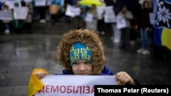 A child holds a sign saying "demobilization" in Ukrainian during a protest by soldiers' families in November 2023.