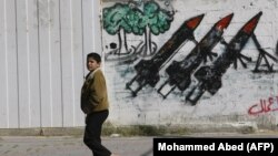 Rakétarajzok előtt sétáló gyermek Gázában