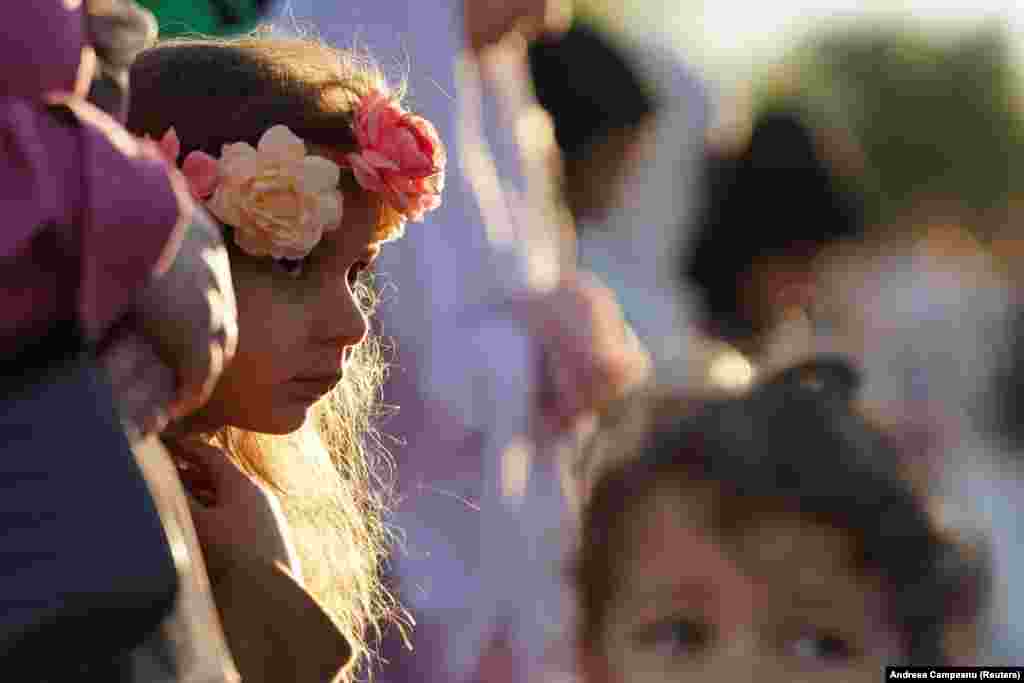 In Bucharest, a little girl wearing a colorful floral headpiece takes part in Eid al-Fitr prayers.