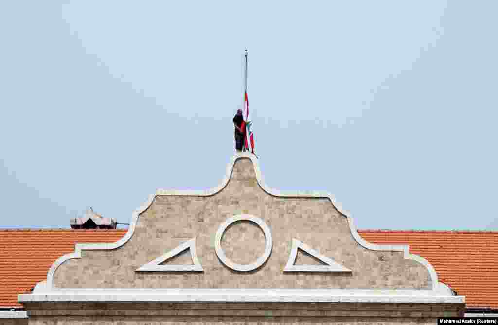 Мужчина приспускает национальный флаг Ливана над правительственным зданием. Временно исполняющий обязанности премьер-министра Наджиб Микати объявил в Ливане трёхдневный траур  