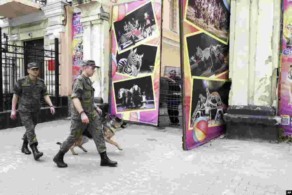 Russian soldiers on June 25 walk past a gate in Rostov-on-Don where a Wagner tank was stationed the day before.&nbsp;