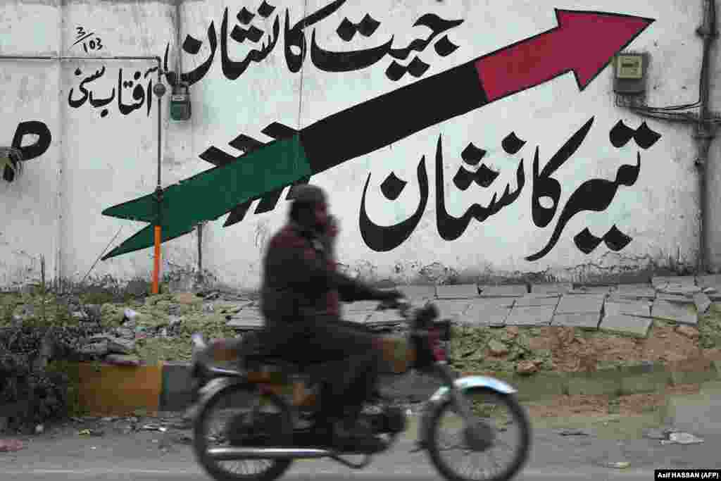 Motociklista prolazi pored zida oslikanog logotipom parlamentaraca Pakistanske narodne partije (PPPP) u obliku strelice duž ulice u Karačiju 12. januara. Izborni simboli i dalje igraju važnu ulogu u osiguravanju glasanja glasača u demokratskom procesu.