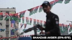 An armed policeman stands guard during an election campaign event in the southern seaport city of Karachi.