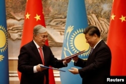 Глава Китая Си Цзиньпин и президент Казахстана Касым-Жомарт Токаев обмениваются документами на встрече в Сиане, Китай, 17 мая 2023 года