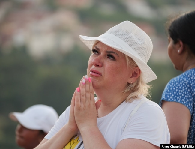 A woman cries in front of the statue of Mary on Apparition Hill on August 3.