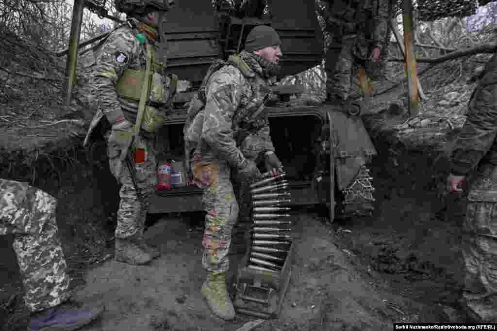 With no drones on the periphery, a soldier works quickly to retrieve antiaircraft shells. &nbsp;