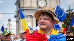 Un tânăr cu steagul Republicii Moldova pe umeri și cel al Uniunii Europene la pălărie participă la un miting pro-UE în Chișinău, pe 21 mai 2023.