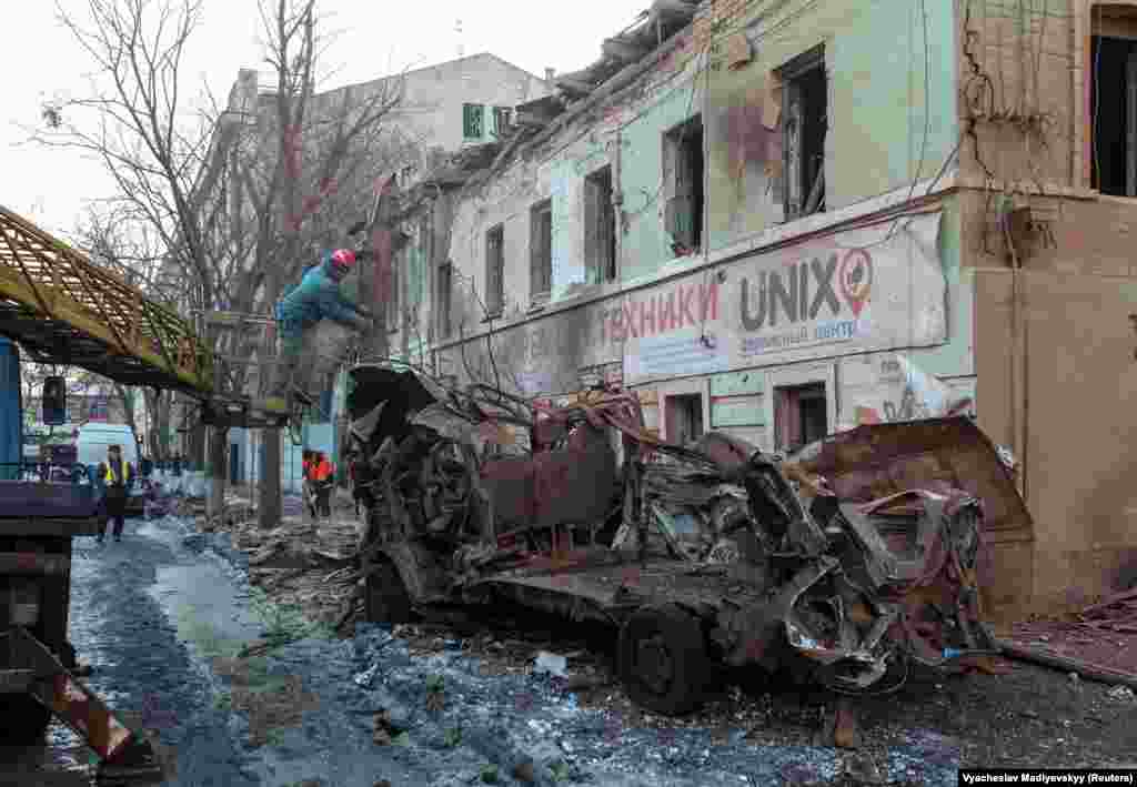 Municipal workers remove the debris from the early morning attack in Kharkiv.