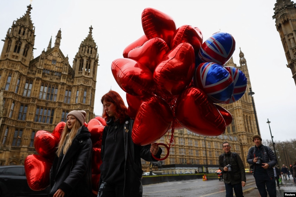 Dy vajza që mbajnë balona të kuq në formë zemre ecin pranë Parlamentit britanik në Ditën e Shën Valentinit në Londër, Britani, më 14 shkurt 2024.