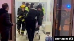 Firefighters evacuate patients at the Perinatal Center in Baku after a fire broke out early on January 9.