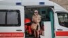 Поранена місцева жителька стоїть у машині швидкої допомоги біля житлових будинків, пошкоджених під час російського ракетного обстрілу у Харкові, Україна, 23 січня 2024 року