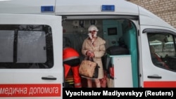 Поранена місцева жителька стоїть у машині швидкої допомоги біля житлових будинків, пошкоджених під час російського ракетного обстрілу у Харкові, Україна, 23 січня 2024 року