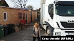 Un camion descarcă marfă în curtea familiei sinistrate Iliescu din Crevedia. În stânga, adăpostul improvizat din containere, în care locuiesc după explozie cei zece membri ai familiei. Pe fundal se văd ruinele casei.