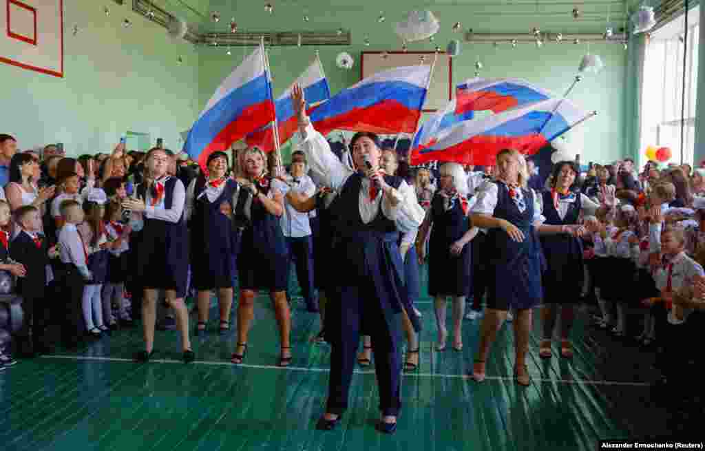 Children watch as people waving Russian flags welcome them to the start of the new school year at a lyceum in Ukraine&#39;s Russian-occupied Donetsk on September 2.