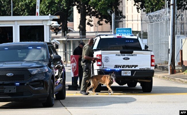 Policajac šeta sa svojim psom K-9 ispred zatvora okruga Fulton u Atlanti, Georgia, 24. avgusta 2023.