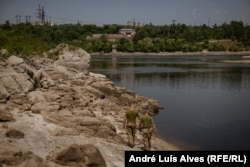 Soldiers walk by the Dnieper River, where the water level dropped approximately 4 meters.