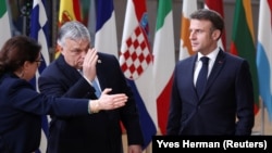 Egy protokollos mutatja az utat Orbán Viktornak és Emmanuel Macronnak a 2024 márciusában tartott uniós csúcson