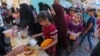 Gra e fëmijë palestinezë të zhvendosur duke pritur në radhë për të marrë ushqim.
