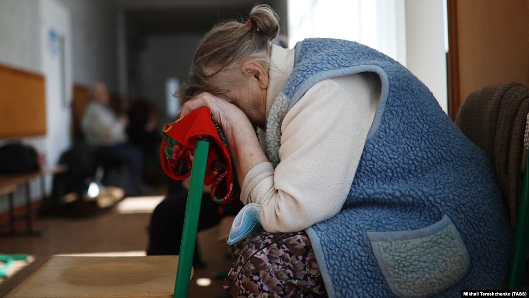 A woman rests her head at a temporary accommodation center for evacuated residents in Volodarskoye, 25 kilometers from the city of Mariupol in Russian-occupied Ukraine, in March 2022. 