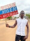 Сторонник правящей хунты Нигера держит табличку в цветах российского флага с надписью "Да здравствует Россия, да здравствуют Нигер и жители Нигера". Ниамей, 3 августа 2023 года