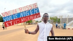 Сторонник хунты Нигера держит плакат в цветах российского флага с надписью «Да здравствует Россия, да здравствует Нигер и нигерийцы» во время акции 3 августа 2023 года