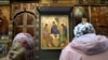 Women pray in front of Andrei Rublev's 15th-century icon Trinity 