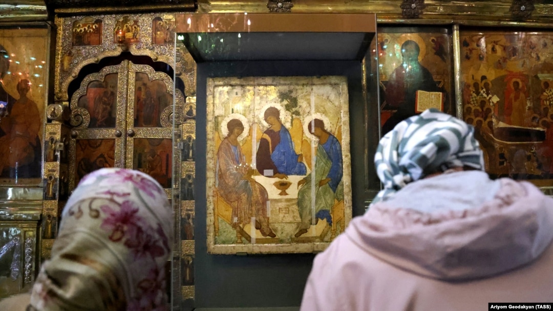 Women pray in front of Andrei Rublev's 15th-century icon Trinity 