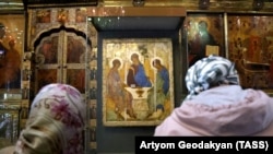 Women pray in front of Andrei Rublev's 15th-century icon Trinity 