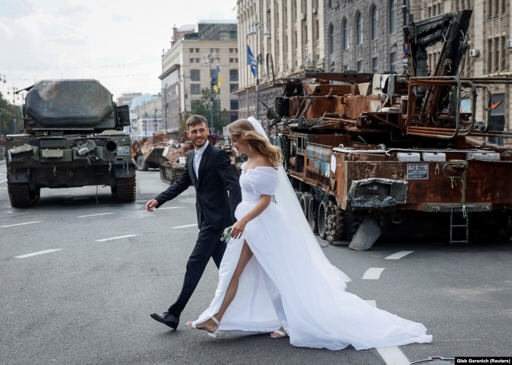 Një çift ukrainas i sapomartuar viziton një ekspozitë në Kiev ku u shfaqën automjete ushtarake ruse të shkatërruara.