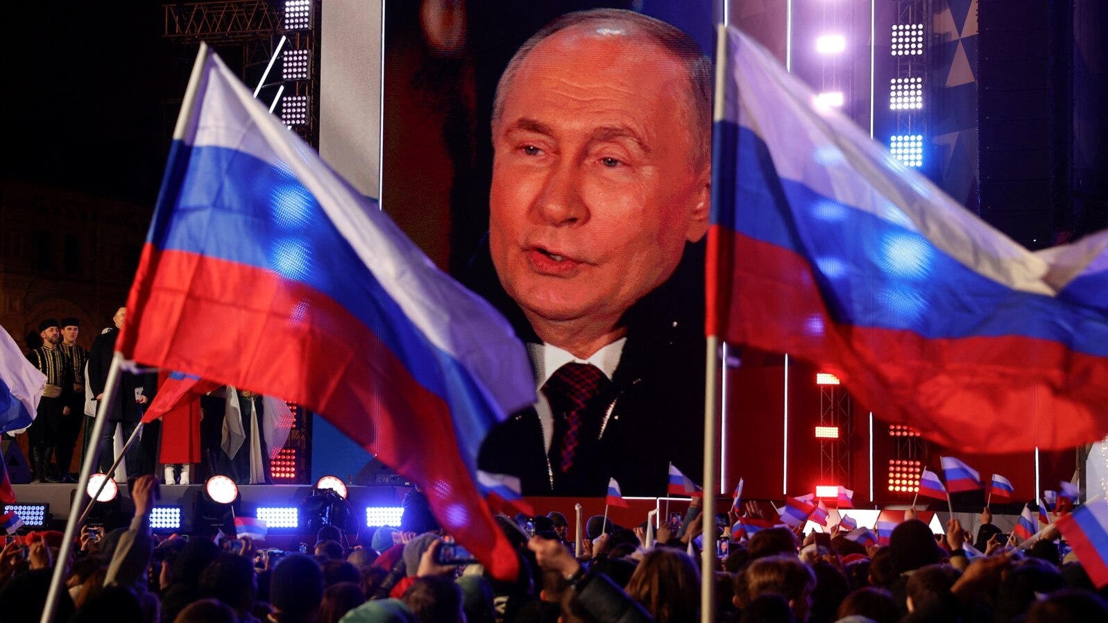 Președintele rus Vladimir Putin apare pe un ecran de pe scenă, în timp ce participă la un miting care marchează cea de-a 10-a aniversare de la ocuparea Crimeei ucrainene de către Rusia, Piața Roșie din centrul Moscovei, pe 18 martie.