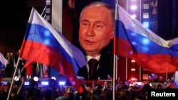 Președintele rus Vladimir Putin apare pe un ecran de pe scenă, în timp ce participă la un miting care marchează cea de-a 10-a aniversare de la ocuparea Crimeei ucrainene de către Rusia, Piața Roșie din centrul Moscovei, pe 18 martie.