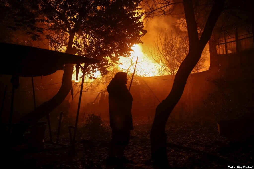 Un residente osserva le case bruciare.  L’ultima ondata di attacchi aerei russi sulle infrastrutture arriva mentre crescono i timori che Mosca stia cercando di paralizzare la rete energetica dell’Ucraina mentre le temperature precipitano in inverno.