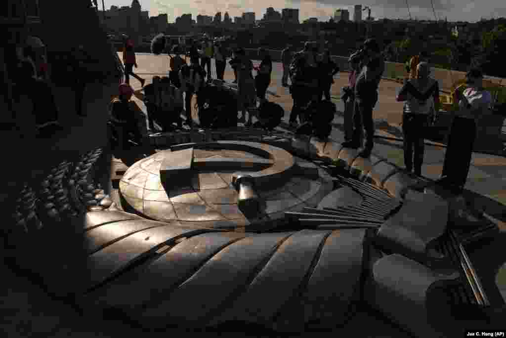 Members of the media surround a Soviet emblem removed from the shield of the Motherland Monument in Kyiv.