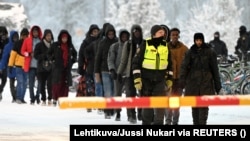 Finnish border guards escort migrants at the border crossing with Russia at Salla on November 23, 2023. Finland has accused Russia of funneling migrants to its border.