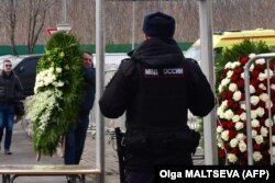 Čovek s vencem prolazi kroz detektor metala na ulazu u groblje Borisovsko uoči sahrane opozicionog lidera Alekseja Navaljnog, 1. mart 2024.