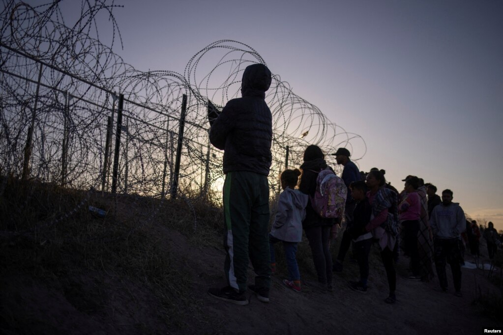 Emigrantët shikojnë përtej një gardhi telash gjemborë në El Paso, Teksas, SHBA, 24 mars 2024.