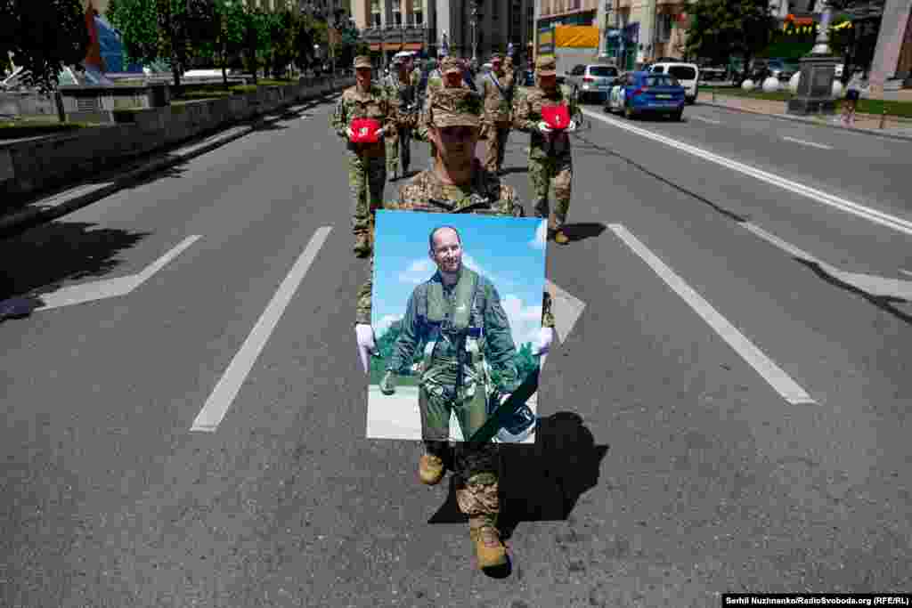 Soldați ucraineni poartă pe străzile Kievului un portret al pilotului decedat.