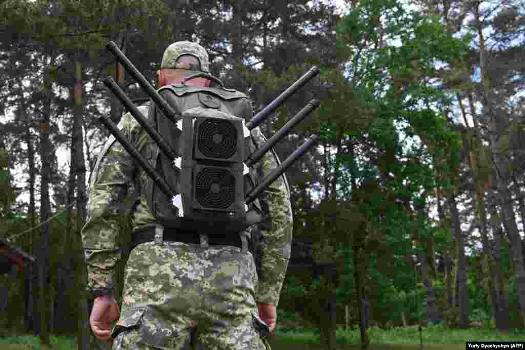 Un soldat ucrainean poartă un &bdquo;rucsac anti-drone&rdquo; în timpul unei demonstrații de dispozitive de bruiaj în regiunea Lvov, în luna mai 2024.