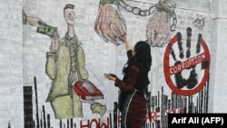 Studentica umjetnosti slika mural protiv korupcije na ulici u Lahoreu, Pakistan, novembar 2023.