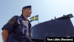 Një detare duke qëndruar pranë nëndetëses suedeze HMS Gotland, në një port në bazën detare Karlskrona, në Suedi, më 25 maj 2023.