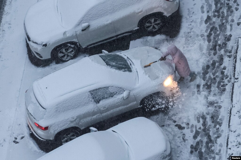 Një grua duke larguar borën nga një veturë në Kiev, Ukrainë, 22 nëntor 2023.