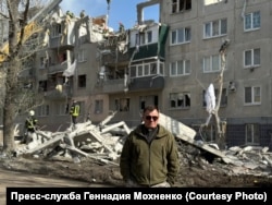 Мохненко на фоне разрушенного здания
