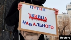 Жінка тримає плакат з написом «Путін – убивця Навального» під час мітингу пам’яті російського опозиціонера Олексія Навального в Москві, 17 лютого 2024 року