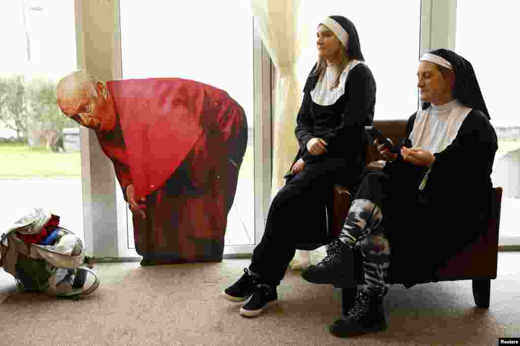 Žene u kostimima sjede pored kartonske slike &quot;Biskupa Brennana&quot; na TedFestu, godišnjoj konvenciji obožavatelja sitcoma Father Ted, u Inis Moru, Irska, 9. marta.