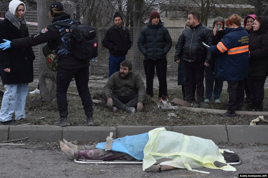 Un uomo siede sconsolato mentre gli astanti reagiscono alla morte di una donna uccisa nell'attacco aereo a Zaporizhzhya.     