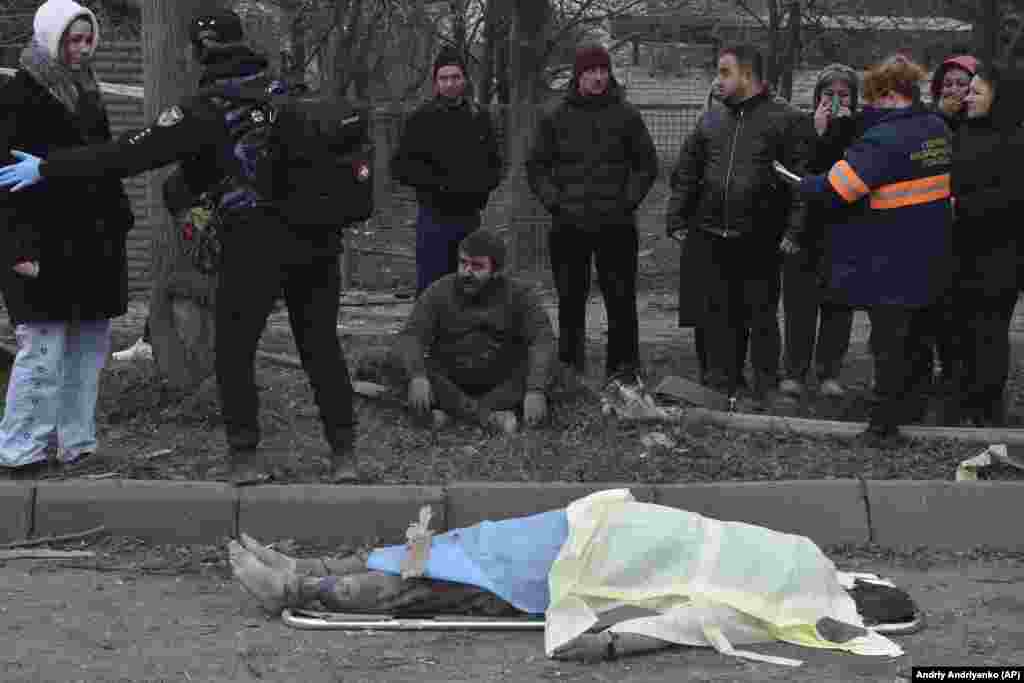 A man sits dejectedly as bystanders react to the death of a woman killed in the air attack in Zaporizhzhya.&nbsp;&nbsp; &nbsp;