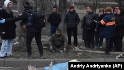 Львов шаарында орус армиясынын жапырт аба соккуларынан өмүрү кыйылган кишинин жанында топтолгондор. 29-декабрь, 2023-жыл.