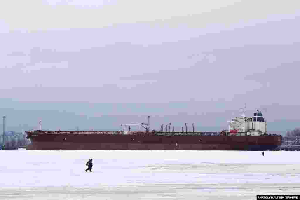 Fishermen walk while ice fishing on the Gulf of Finland in front of an oil tanker in St. Petersburg, Russia.&nbsp;